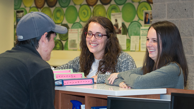 A desk assistant chats with RAs at the front desk of a residence hall
